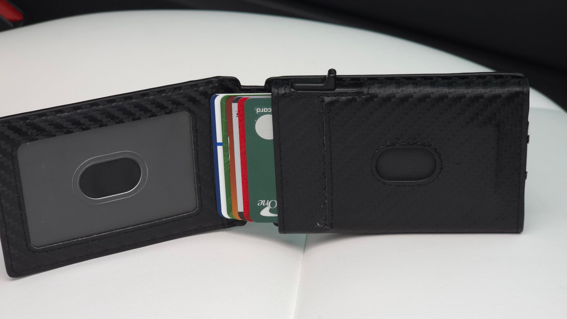 Altus EDC minimalist wallet displaying the unique quick-flip ID window feature for instant verification, alongside the automotive-grade carbon weave finish and 12-card chamber capacity, with cards ejected, staged on a white luxury vehicle seat.